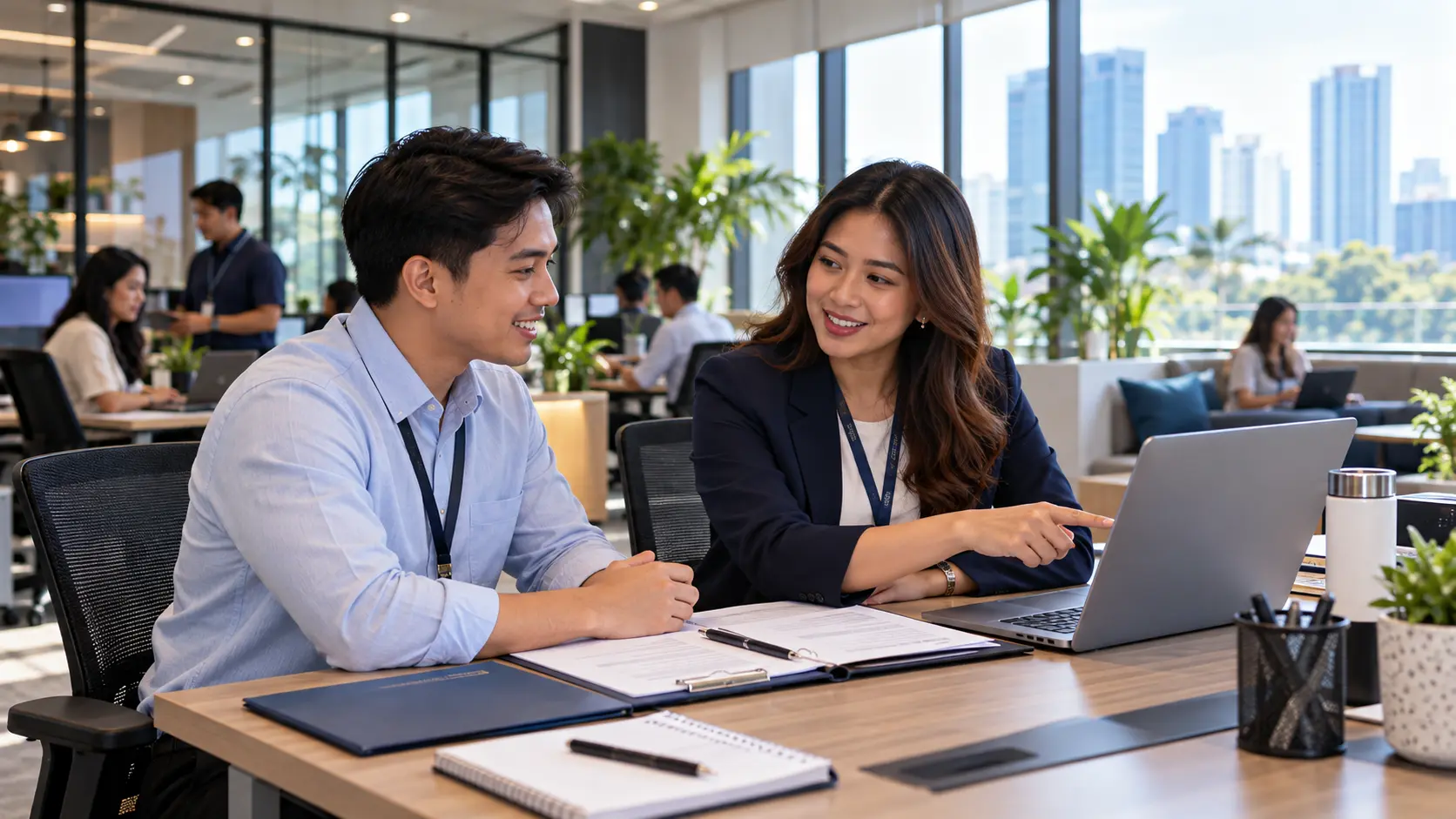 An HR officer and a new employee going through onboarding papers together at an office table